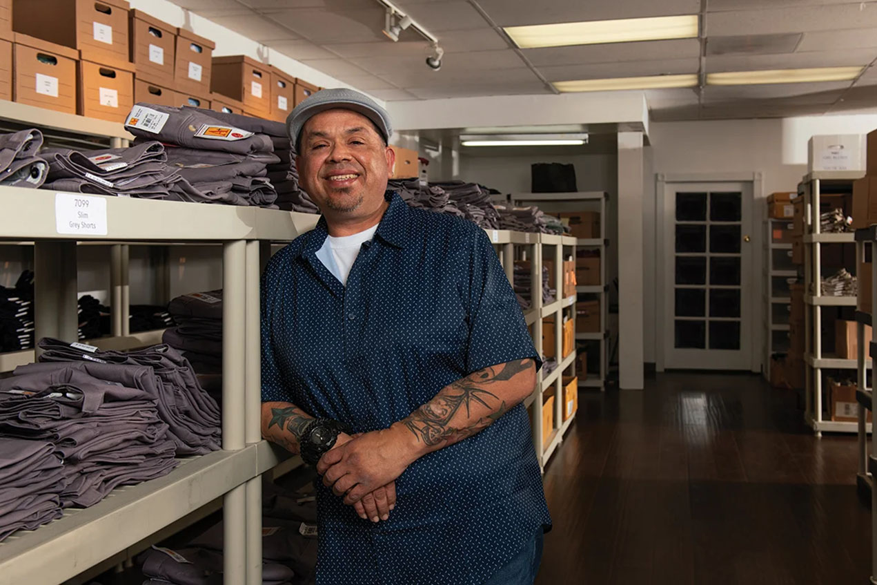 A man leans against a shelf in an industrial clothing store